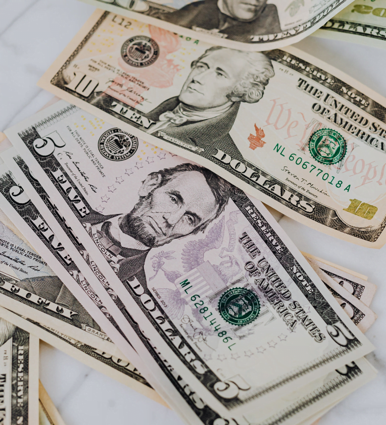 a pile of five, ten, and twenty dollar bills on a white table